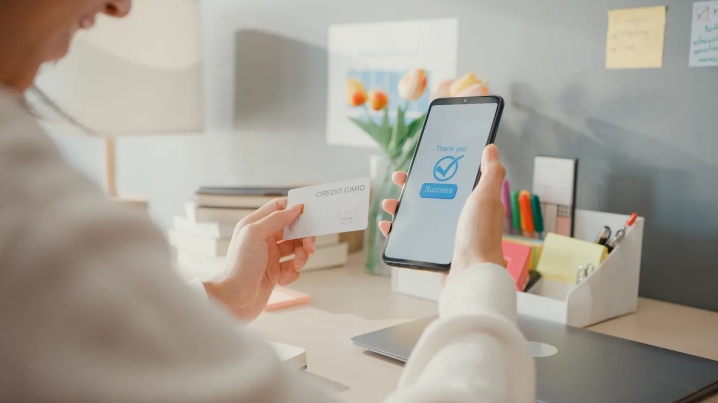 A shopper confirming a payment on a phone while holding a card