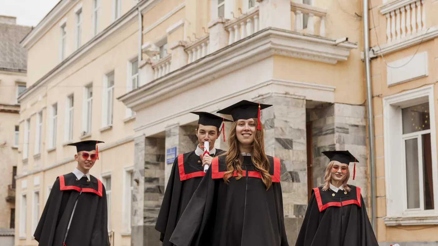 Graduates in caps and gowns walking out of a university building
